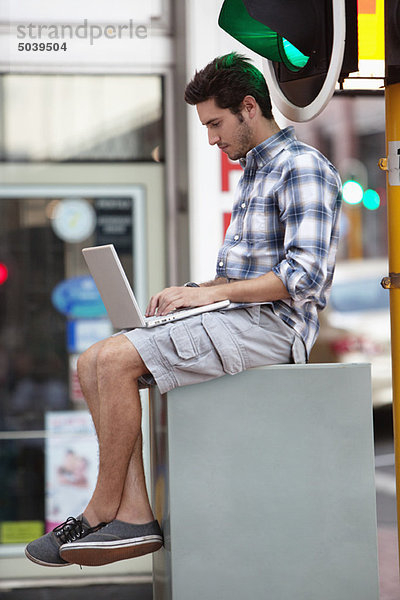Mann mit einem Laptop in der Nähe einer Ampel
