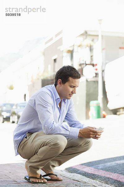 Mann kauernd und Textnachrichten auf einem Handy