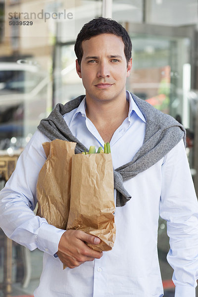 Porträt eines erwachsenen Mannes mit Papiertüten voller Gemüse