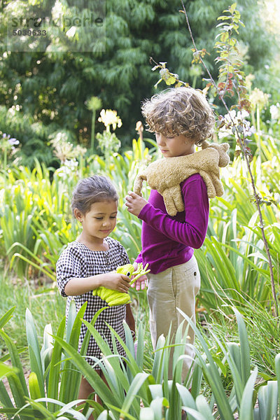 Süßer kleiner Junge steht mit kleinem Mädchen in einem Garten