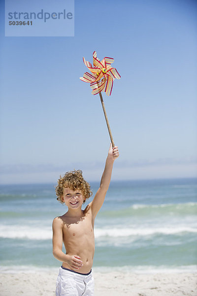 Porträt eines Jungen mit einem Windrad am Strand