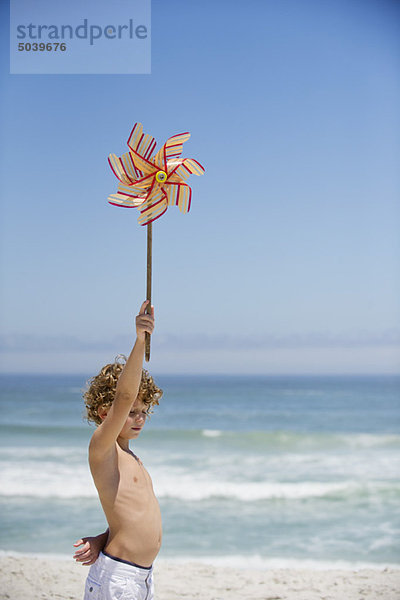 Seitenprofil eines Jungen mit einem Windrad am Strand