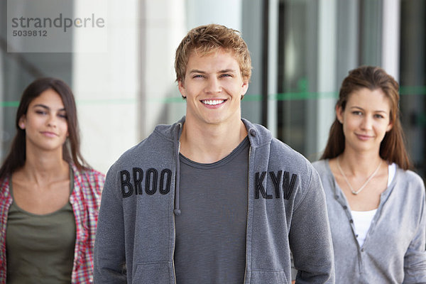 Porträt von drei lächelnden Freunden auf dem Campus