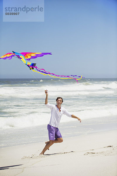 Mittlerer Erwachsener Mann beim Drachenfliegen am Strand