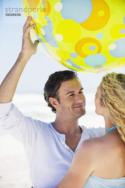 Ein Mann hebt einen Strandball mit einer Frau in seiner Nähe.