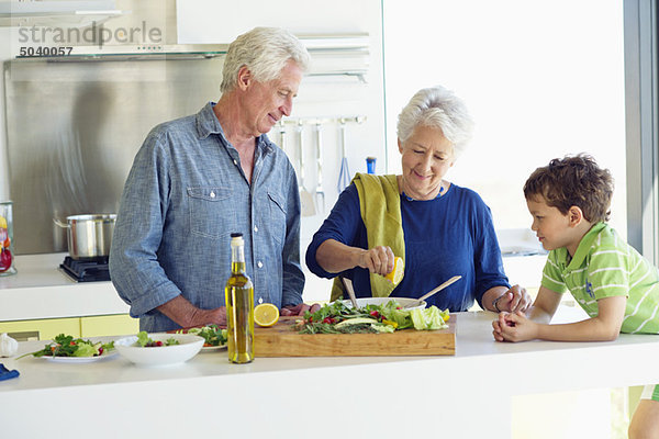 Seniorenpaar mit ihrem Enkel an der Küchentheke