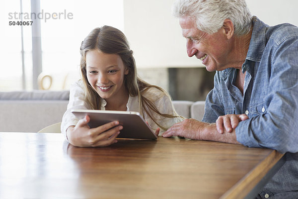 Mädchen mit einem digitalen Tablett  bei dem ihr Großvater in ihrer Nähe sitzt.