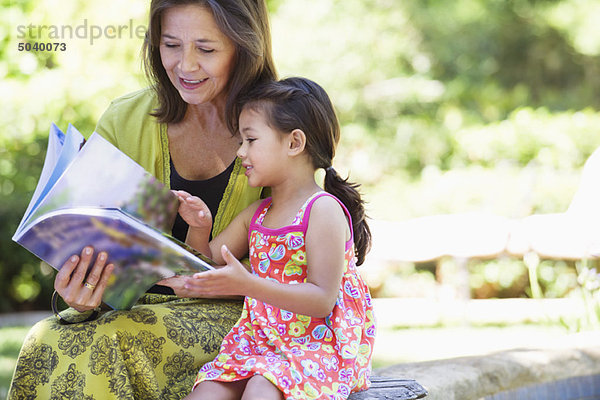 Frau mit ihrer Enkelin beim Betrachten eines Buches