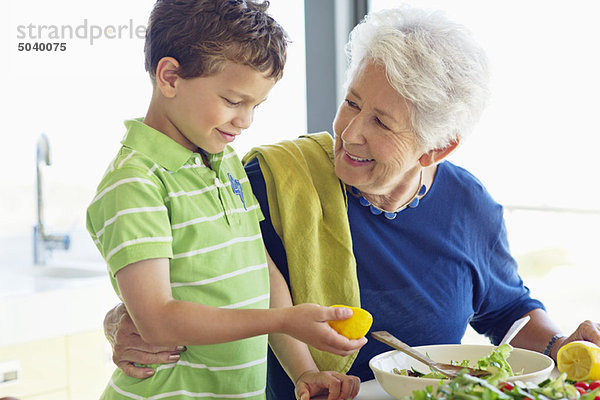 Seniorin bei der Zubereitung des Essens in der Küche mit ihrem Enkel