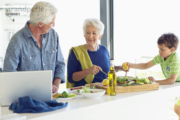 Seniorenpaar mit ihrem Enkel bei der Zubereitung des Essens in der Küche