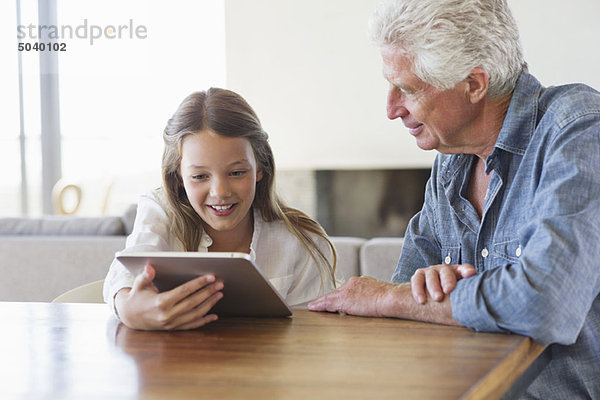Mädchen mit einem digitalen Tablett  bei dem ihr Großvater in ihrer Nähe sitzt.