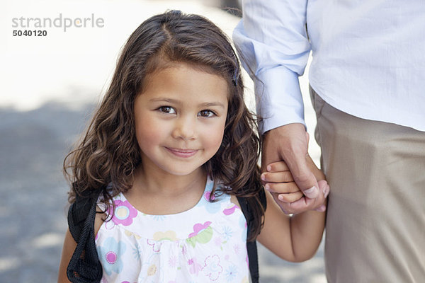 Porträt eines kleinen Mädchens  das die Hand seines Vaters hält.