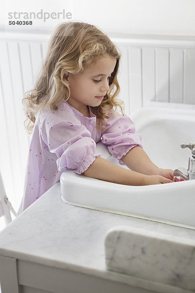 Süßes kleines Mädchen  das sich die Hände im Waschbecken wäscht.