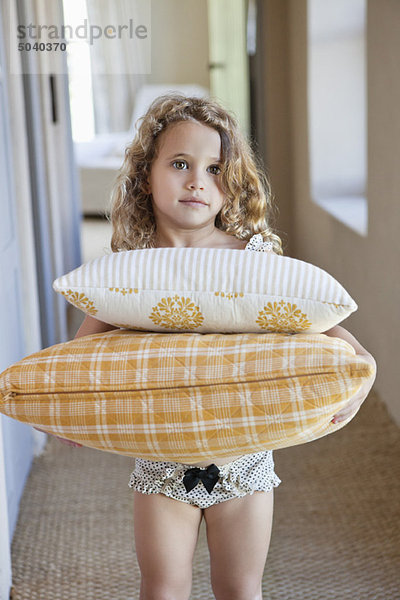 Porträt eines süßen kleinen Mädchens mit Kissen zu Hause