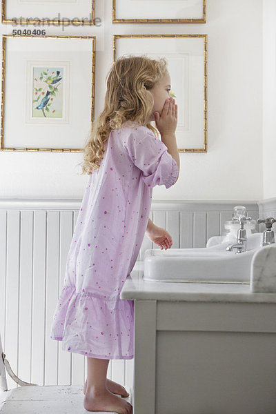 Süßes kleines Mädchen  das sein Gesicht im Badezimmer wäscht.