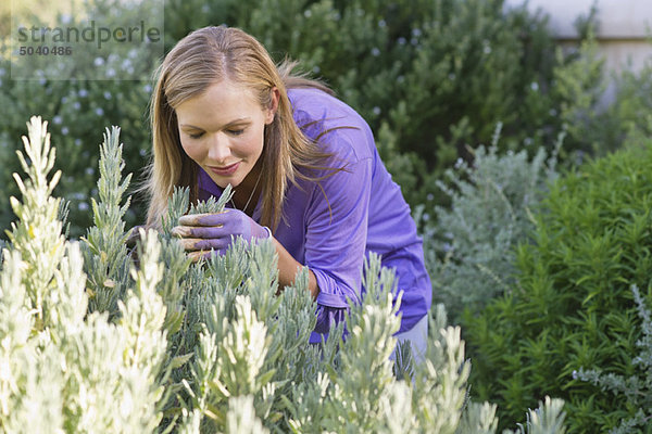 Junge Frau riecht Blumen im Garten