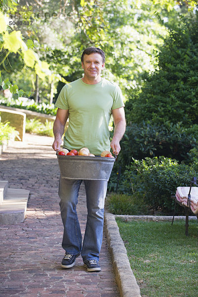 Reifer Mann mit Obstkorb im Garten