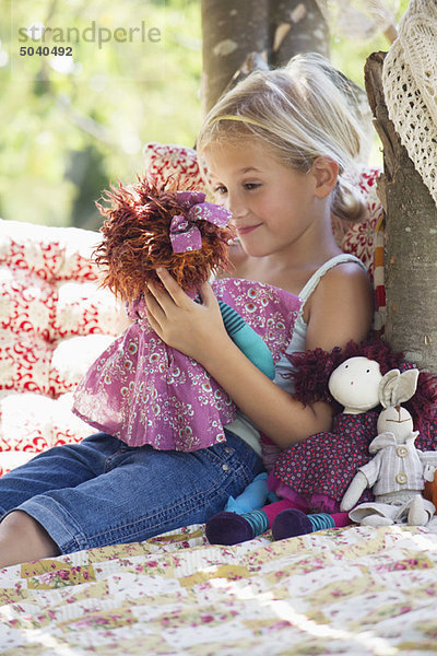 Lächelndes kleines Mädchen mit Spielzeug im Baumhaus