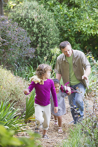 Vater mit zwei Kindern bei einem Spaziergang im Garten
