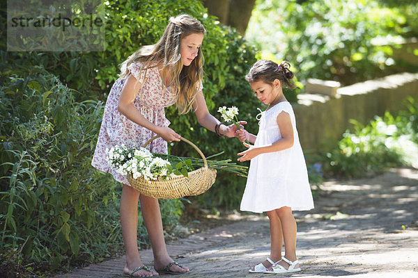 Mädchen schenkt ihrer kleinen Schwester eine Blume.