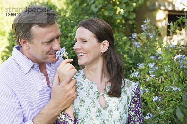 Ein glückliches reifes Paar  das im Garten Blumen riecht.