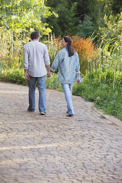 Rückansicht eines reifen Paares beim Spaziergang im Garten