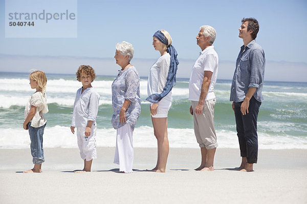 Familie steht in Reihe am Strand mit Kindern