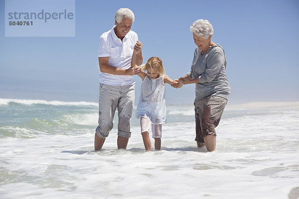 Enkelin genießt mit Großeltern am Strand