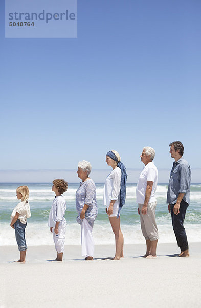 Familie steht in Reihe am Strand mit Kindern