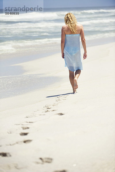 Rückansicht einer am Strand spazierenden Frau