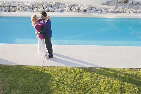 Mittleres erwachsenes Paar  das sich am Pool umarmt