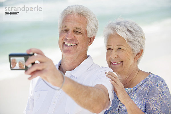Glückliches Seniorenpaar beim Fotografieren mit einer Digitalkamera