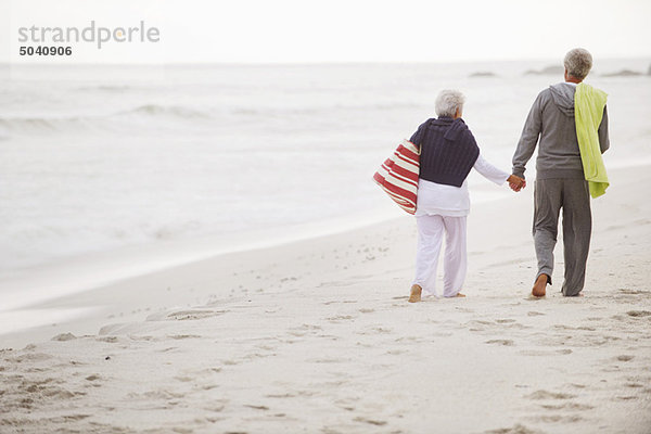 Rückansicht eines Seniorenpaares beim Spaziergang am Strand
