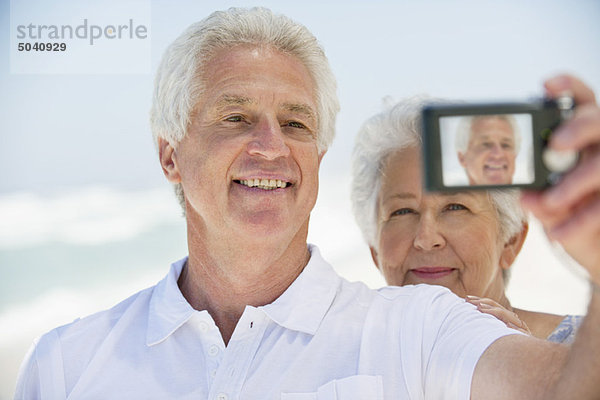 Glückliches Seniorenpaar beim Fotografieren mit einer Digitalkamera