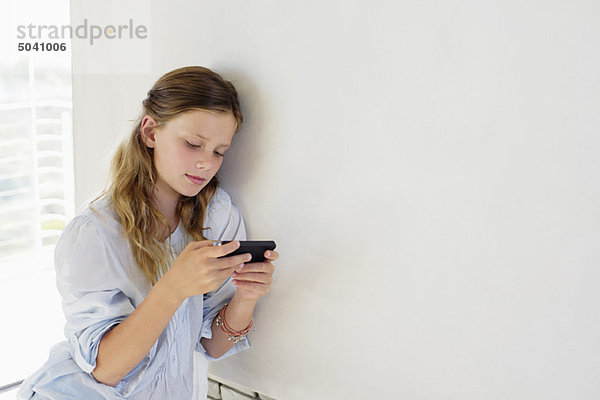 Mädchen beim Spielen mit einem Handheld-Videospiel zu Hause