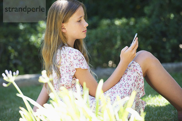 Süßes kleines Mädchen mit einem Handy im Freien