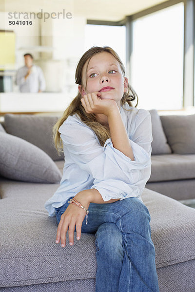 Mädchen auf einer Couch sitzend und nachdenkend