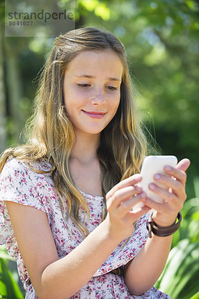 Lächelndes kleines Mädchen SMS mit Hilfe eines Mobiltelefons