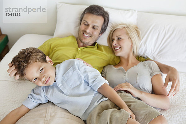 Eltern mit ihrem Sohn entspannt im Bett