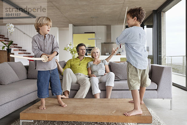 Jungen  die mit ihren Eltern auf einer Couch sitzen.