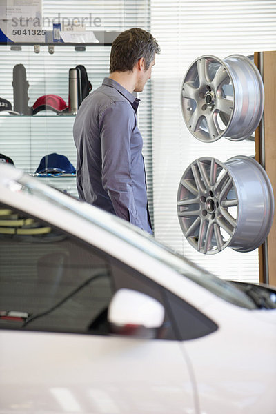 Mittlerer Erwachsener Mann schaut sich die Radkappe im Autohaus an.