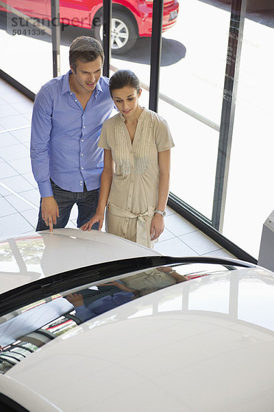 Ein Paar schaut sich ein Auto in einem Ausstellungsraum an.