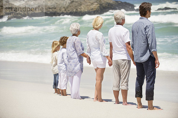 Rückansicht einer am Strand stehenden Mehrgenerationen-Familie