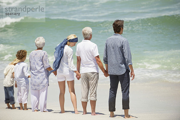 Mehrgenerationen-Familie in einer Reihe am Strand stehend
