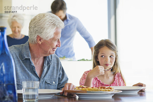 Mädchen beim Essen am Esstisch  ihr Großvater sitzt neben ihr.