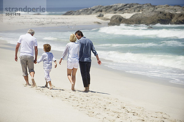 Rückansicht einer Mehrgenerationen-Familie beim Spaziergang am Strand