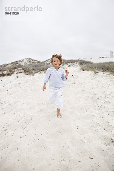 Süßer Junge läuft auf Sand am Strand
