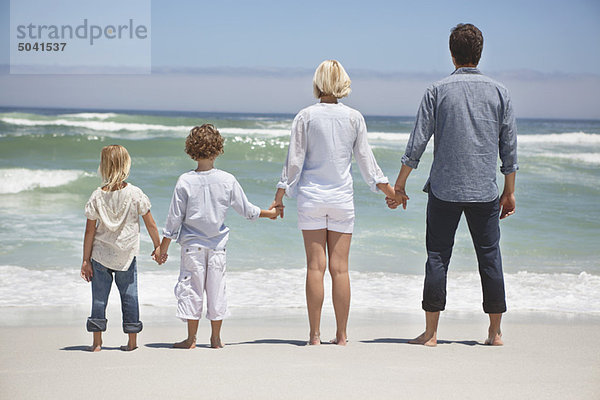 Familie mit Blick auf das Meer vom Strand aus