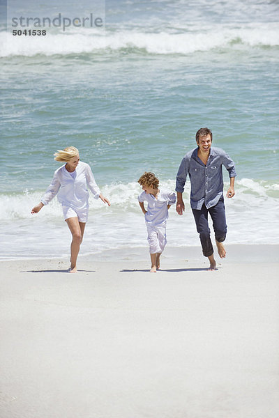 Paar mit ihrem Sohn  der am Strand rennt.