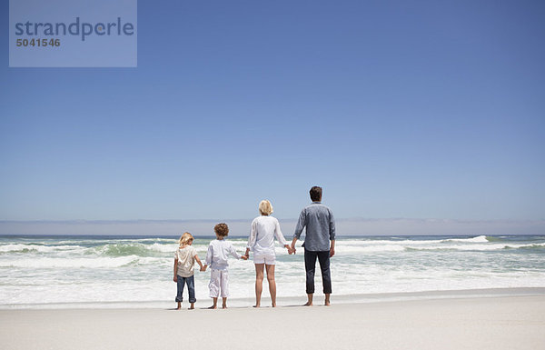 Familie mit Blick auf das Meer vom Strand aus